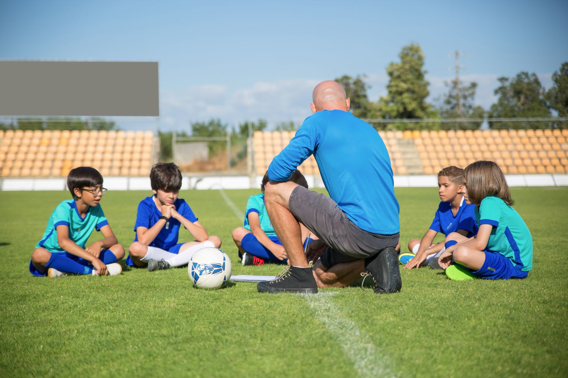Entrenador joven dirigiendo un entrenamiento de fútbol con un grupo de niños