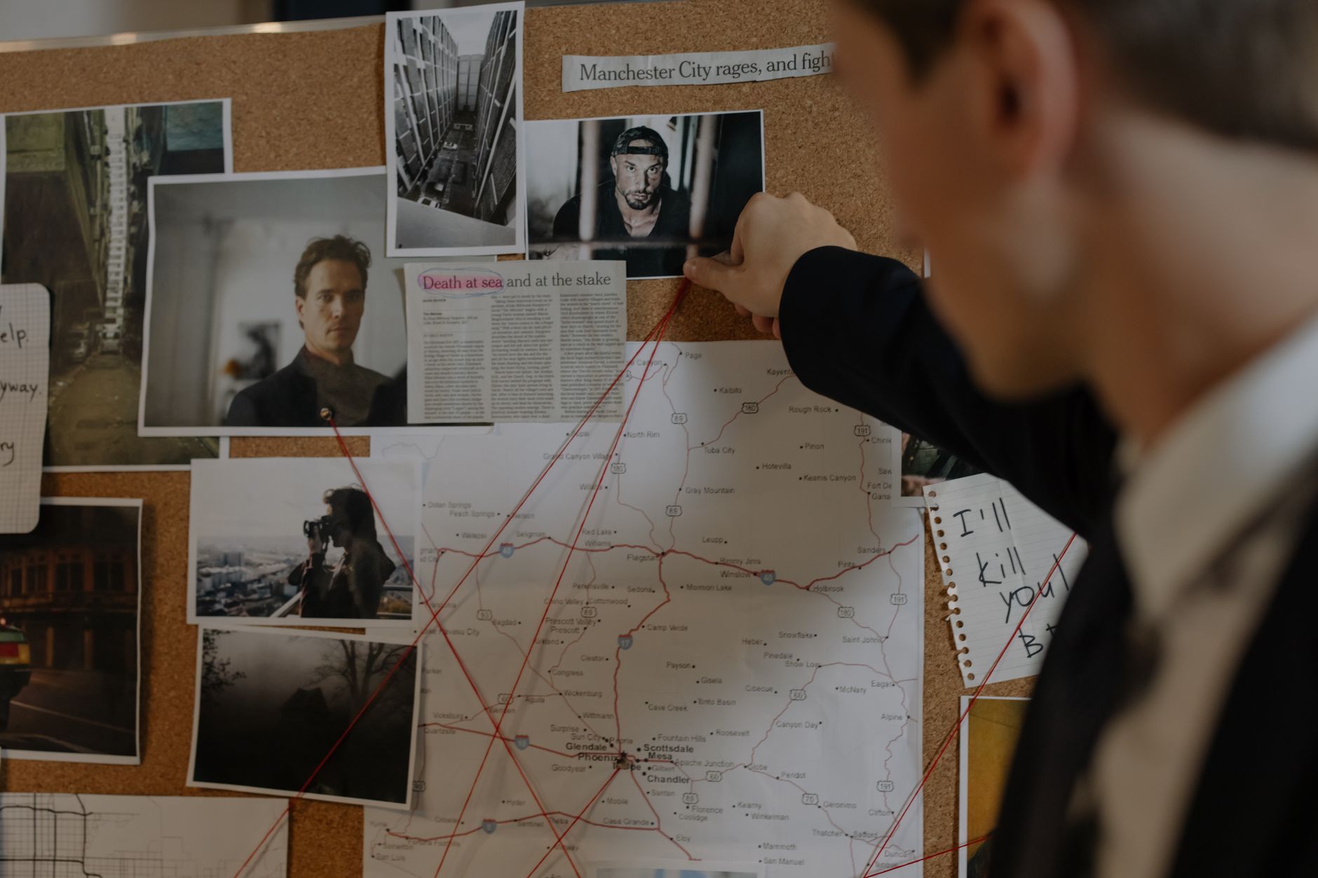 Analista joven estudiando un panel de investigación con fotografías, mapas y notas