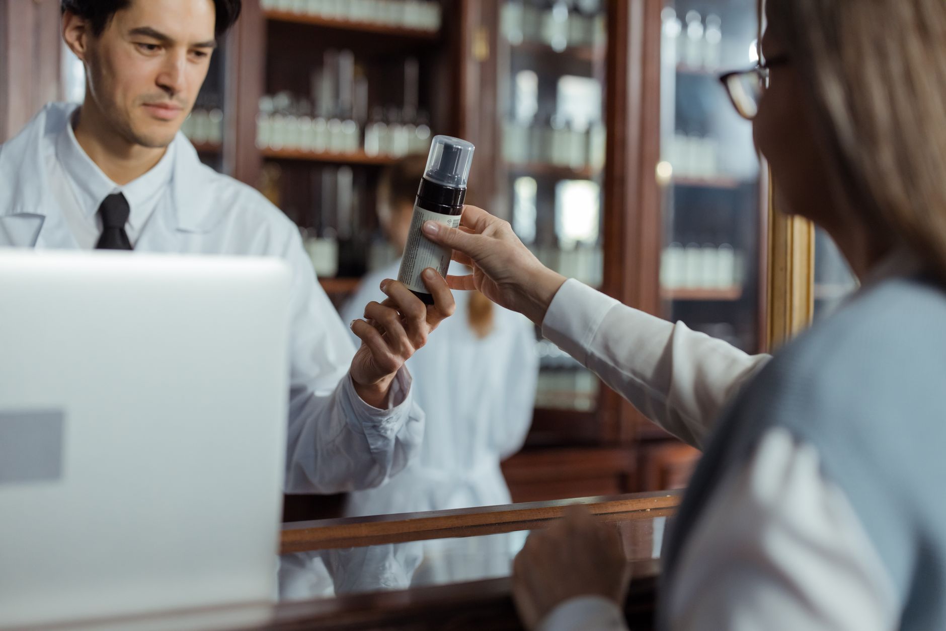 Farmacéutico joven entregando un medicamento a una clienta en el mostrador de una farmacia